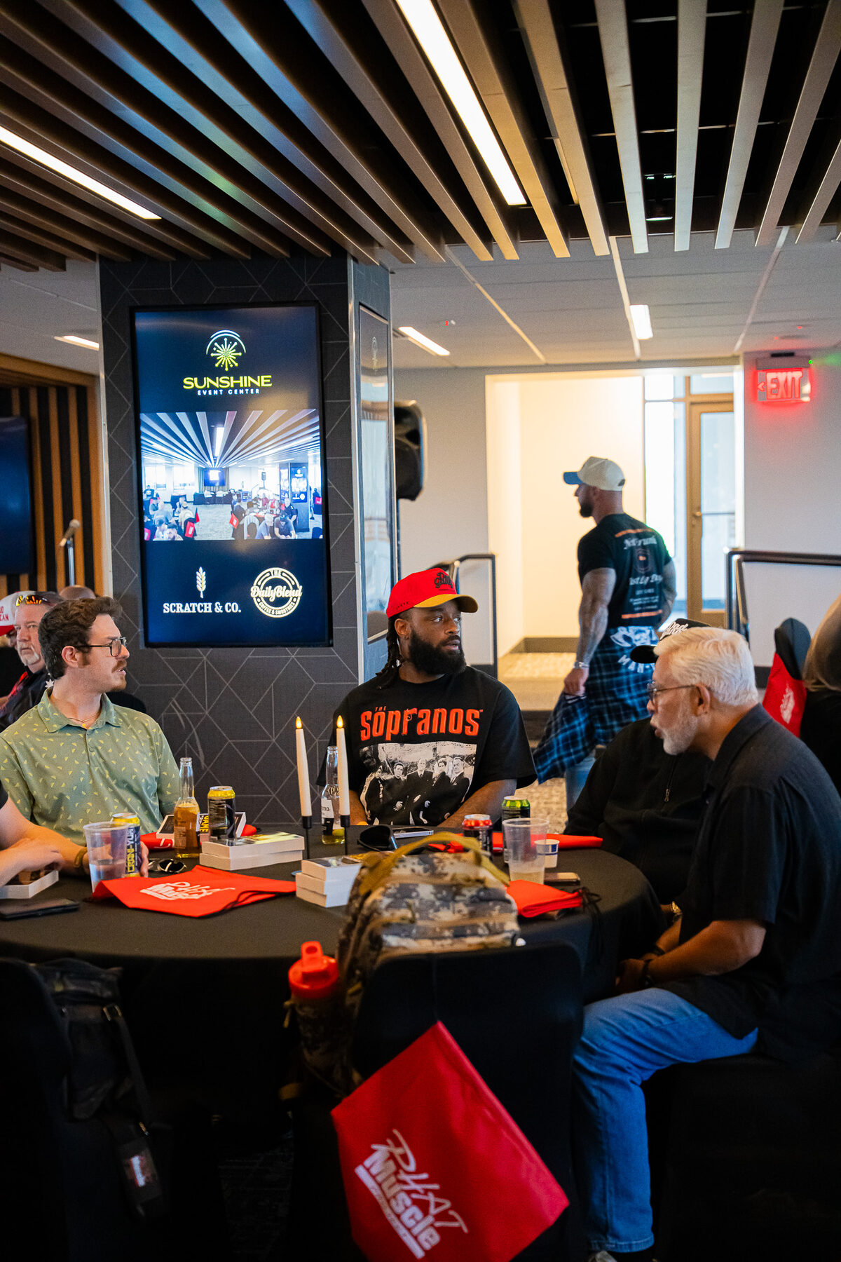 A small group of men seated around a table in focused conversation during a Man Days Project accountability session